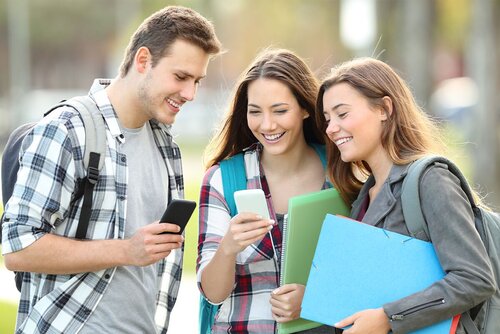 Drei Schüler stehen gemeinsam und schauen in ein Handy 