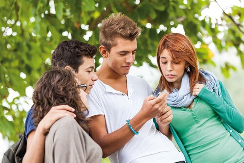Vier Jugendliche schauen in ein Handy 