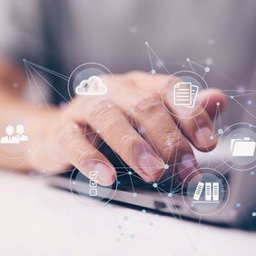 Eine Hand am Laptop tippend und vernetzte Symbole 