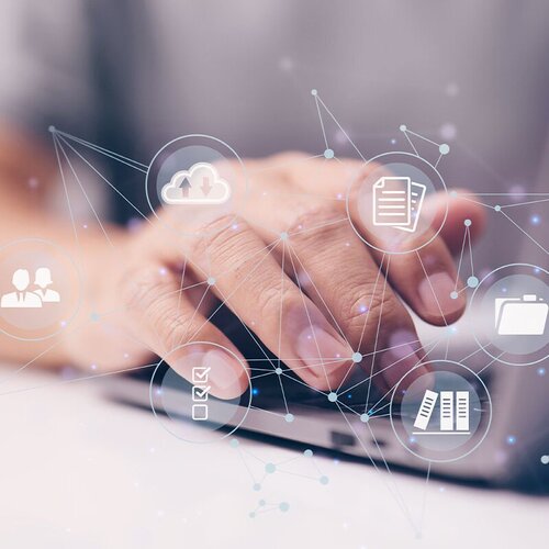 Eine Hand am Laptop tippend und vernetzte Symbole 