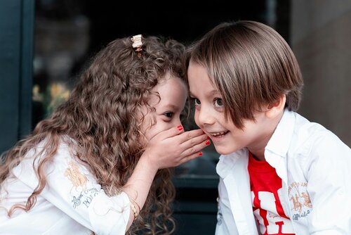Mädchen flüstert Jungen etwas ins Ohr